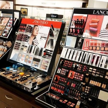 Kosmetikdisplays mit einer Vielzahl von Make-up-Produkten von Shiseido und Lancôme, übersichtlich angeordnet auf schwarzen Ständern