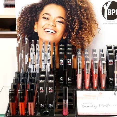 Eine Auslage mit Lippenprodukten in verschiedenen Lippenstift- und Gloss-Farbtönen, die übersichtlich in einem Regal mit Branding-Motiven angeordnet sind