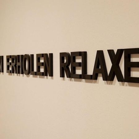 In schwarzen Buchstaben auf einer weißen Wand steht : ENTSPANNEN ERHOLEN RELAXEN