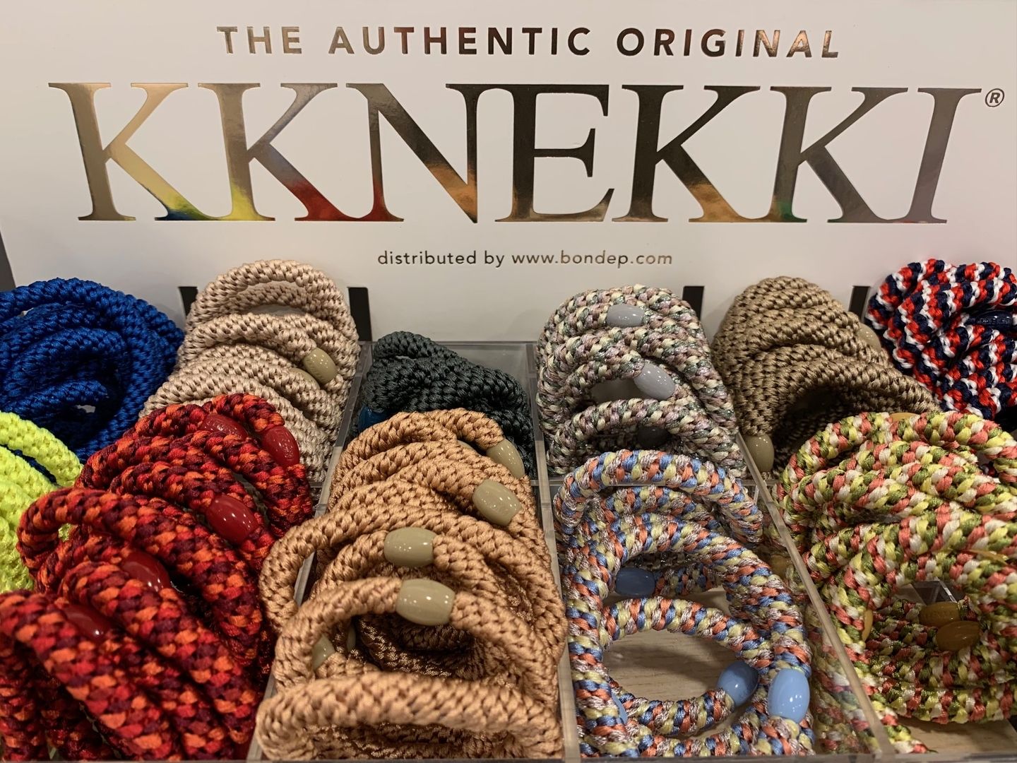 Eine Auslage mit bunten geflochtenen Armbändern in verschiedenen Farbtönen, ordentlich in einem Tablett angeordnet