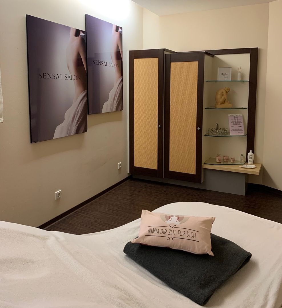 Ein ruhiger Spa-Raum mit beruhigendem Dekor, einem Massagetisch mit Decken und einem Motivationskissen