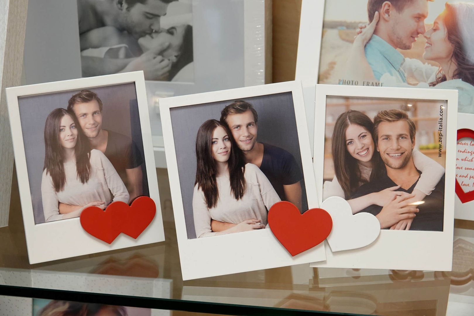 Drei Fotorahmen mit den Porträts von Paaren, die jeweils mit roten Herzen verziert sind